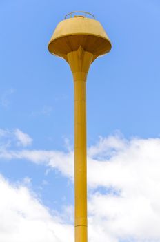 Yellow water tank on blue sky with clouds
