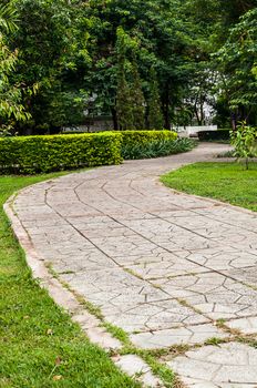 Concrete walkway in the park on green grass