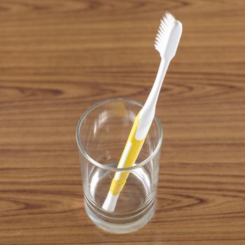 toothbrush in glass on wood background