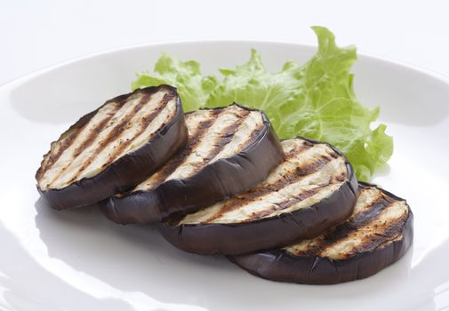 Some fried slices of eggplant with fresh green lettuce on the plate