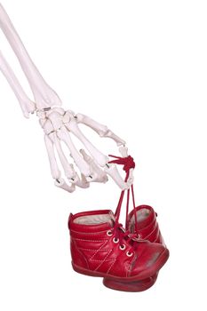 skeleton hand holding old red baby shoes
