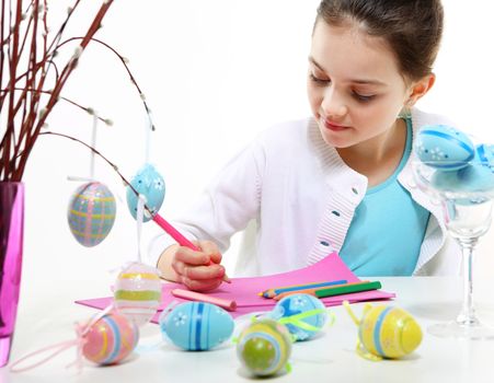 Cute girl decorating Easter eggs