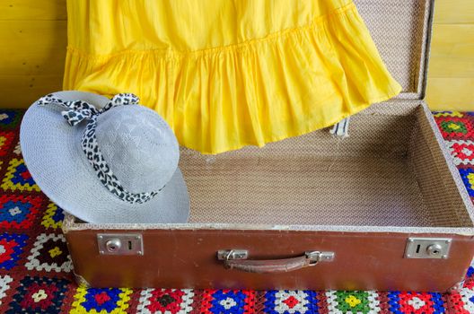 gray straw female hat on suitcase and yellow dresses smocking fragment