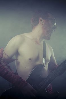 Heavy, rocker man with electric guitar in a rock concert