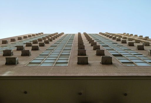 Looking up onto rows of windows and blue sky above