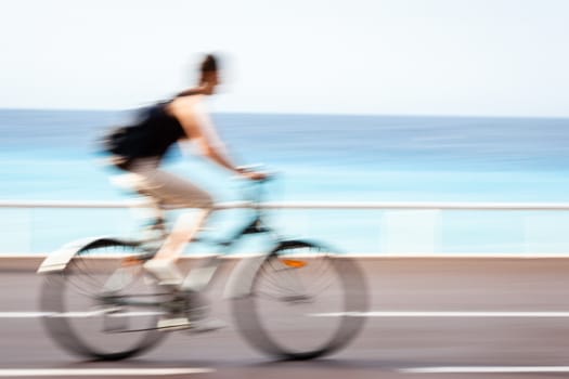 Great way to get around in a city -Motion blurred cyclist going fast on a city bike lane, by the sea shore