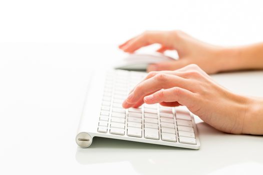 Hands of a person working an a keyboard over white background (color toned image; shallow DOF)