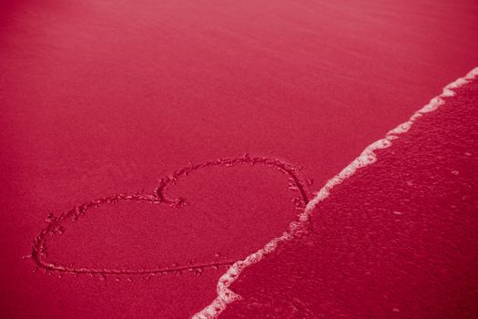 Concept of infidelity or fragile/fugitive/ephemeral love: heart drawn in sand being washed by the sea