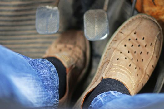 Mans feet pushing on the accelerator of automobile
