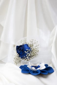 a  blue roses and wedding rings on white background