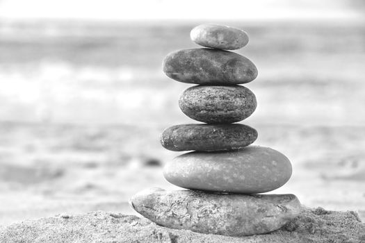 A composition of stacked stones on the beach. Black and white Photo.