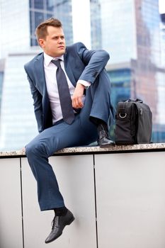 successful businessman resting on a background of office buildings