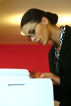 Pretty young businesswoman using Xerox machine at the office 