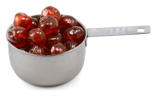 Sticky whole glace cherries in an American cup measure, isolated on a white background