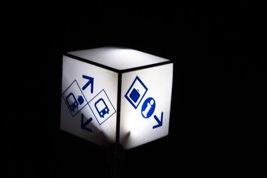 On black background glowing white cube ukazavayuschy on location at the bus station of the information and platform