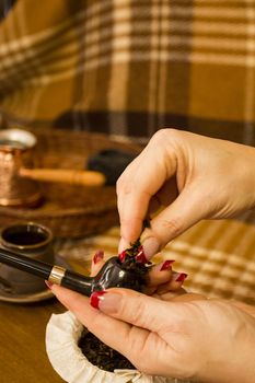 Female hands laying tobacco smoking pipe.