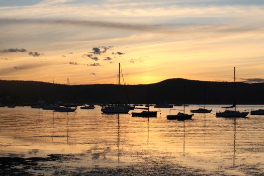 Boats and yachts moored on the tranquil waters at sunset at Saratoga Central Coast, Australia