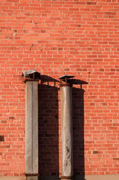 metal pipes to the red brick wall of the house