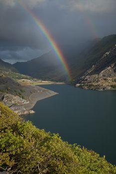 A view across Llyn Peris to Nant Peris and the Llanberis Pass with a double rainbow. Llanberis, Snowdonia national park, Wales, UK