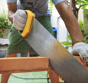 young man sawing wood at home use for diy working and home maintenance in holiday and male activities 