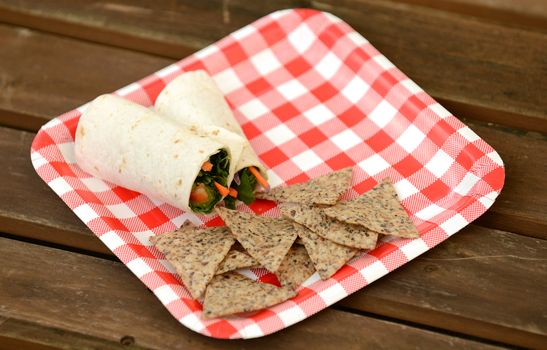 vegan veggie wrap with chips on a paper plate