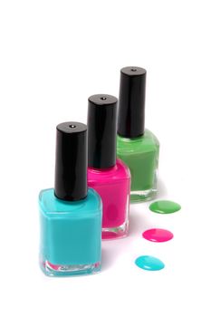 Nail polish bottles and spots in bright spring or summer colors in light blue, pink and green on a white background