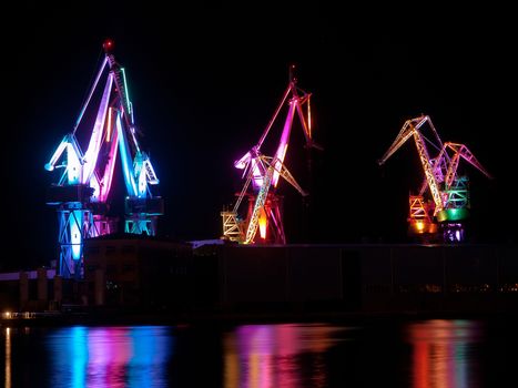 multicolored illumination of shipyard cranes, led lights, night shot