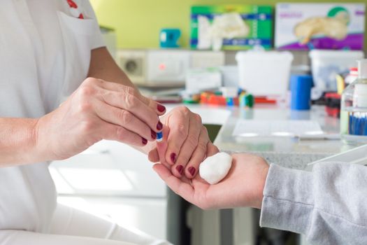 Medical doctor performing a quick prick test for blood group determination by using blood type testing kit with anti A and B antibodies on a white card.