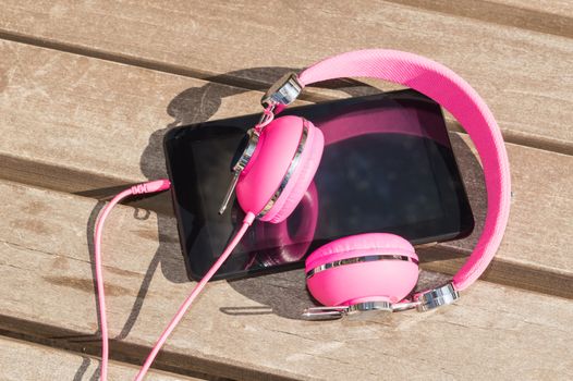 Modern style of distance mobile language study for girls: pink headphones and tablet pc