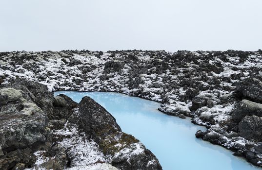 The blue water between the lava stones covered with moss just outside the Blue Lagoon resort of Iceland