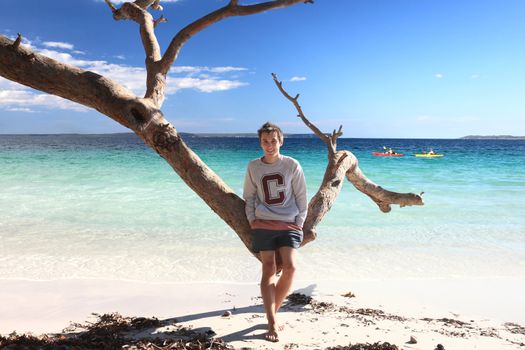 Smiling teen boy on a tropical beach in summer for  relaxing vacation or fun filled leisure on a beautiful sunny day, NSW Australia