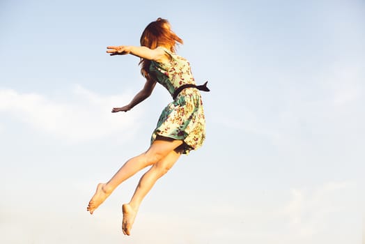 Happy Young Woman Jumping over blue sky