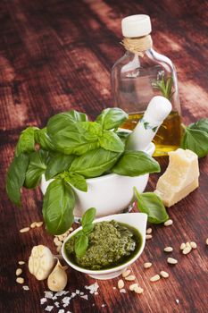 Basil pesto with traditional ingredients on wooden backround. Culinary mediterranean cuisine.