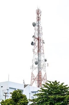 Communications tower on the building with green trees