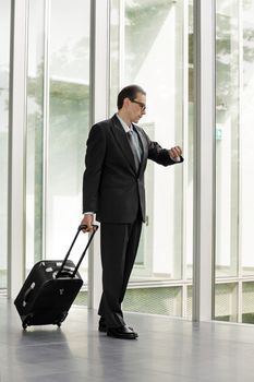 Formal wear Businessman with trolley case looking at his watch