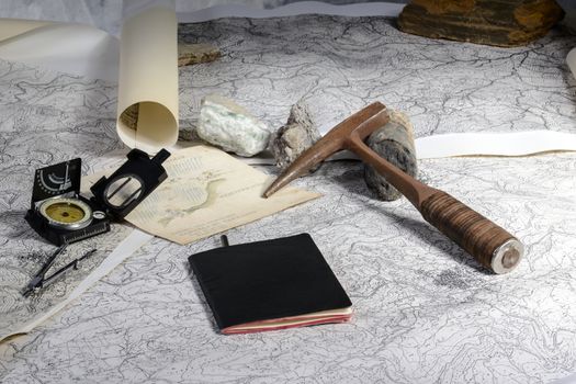 The geological expedition is prepared with the study of topographic maps. On the table the tools of the geologist.