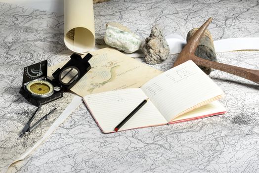 The geological expedition is prepared with the study of topographic maps. On the table the tools of the geologist.