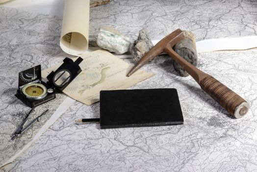 The geological expedition is prepared with the study of topographic maps. On the table the tools of the geologist.