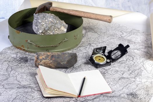 The geological expedition is prepared with the study of topographic maps. On the table the tools of the geologist.