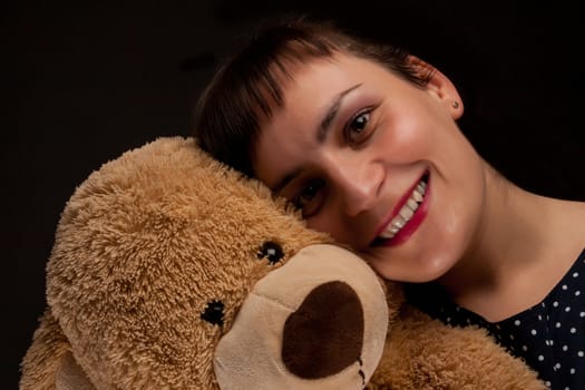 portrait of a stylish expressive woman with teddy bear in studio