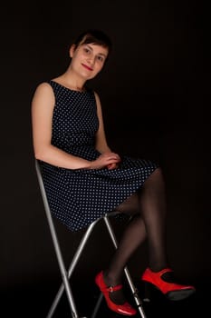 portrait of a stylish expressive woman on chair in studio