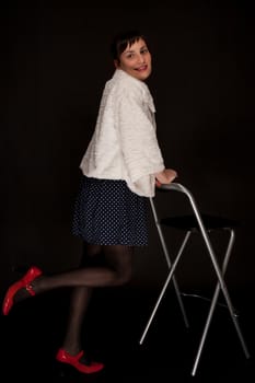 portrait of a stylish expressive woman on chair in studio