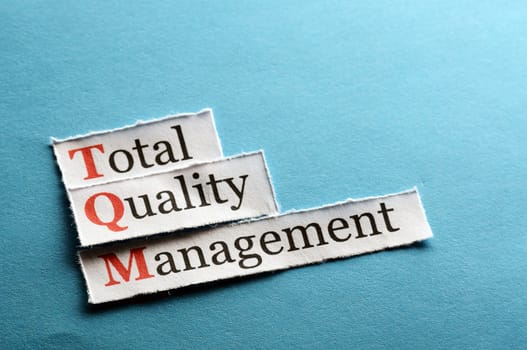 TQM total quality management on blue paper