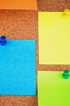 Colorful Sticky Notes with Thumb Tacks closeup on Corkboard