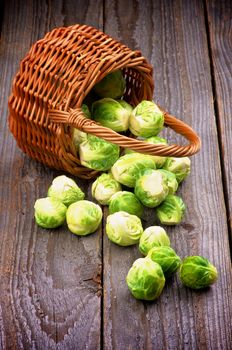 Fresh Raw Brussels Sprouts Scattered from Wicker Basket isolated on Wooden background