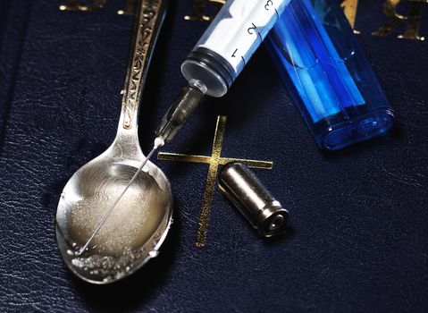 syringe, spoon ,bullet and lighter on the Bible