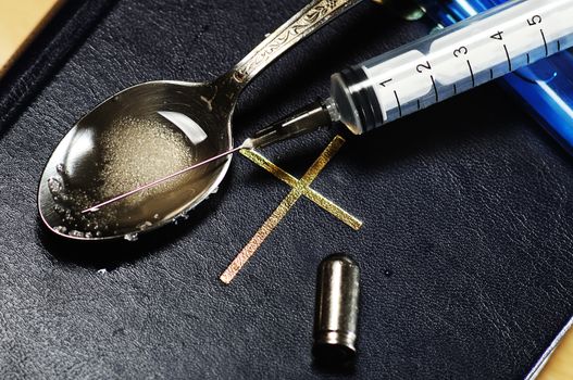 syringe, spoon ,bullet and lighter on the Bible