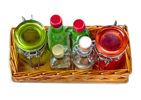 Wicker tray with empty glass jars and little glass bottle, isolated on white background