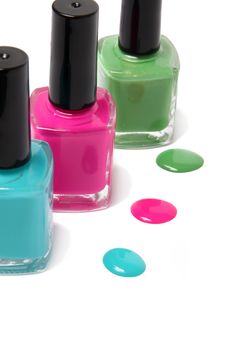 Nail polish bottles and spots in bright spring or summer colors in light blue, pink and green on a white background