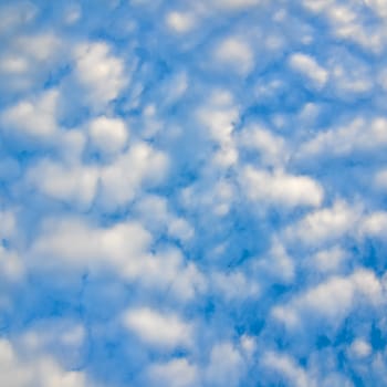 The blue sky and white fluffy clouds .